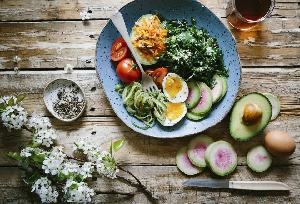 A bowl of greens, eggs, avocado and vegetables